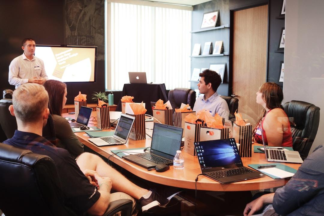 Conference room with employees sitting at a desk and one presenter explaining examples of sales leadership